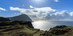 Sheep grazing at the top of the cliffs on Clare Island towards the sun beaming down on the Atlantic Ocean.